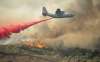 A US Air Force plane drops fire retardant on a burning