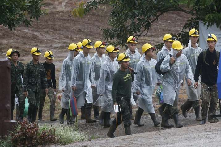 Rescuers walk toward the entrance to a cave complex where