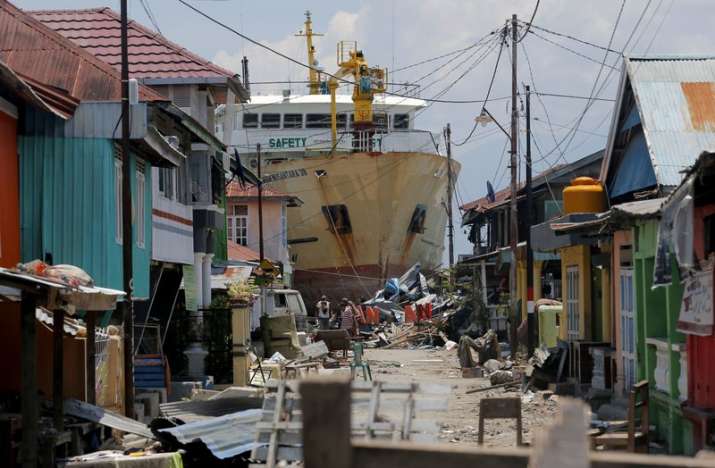 A ship rests near houses after it was swept ashore during