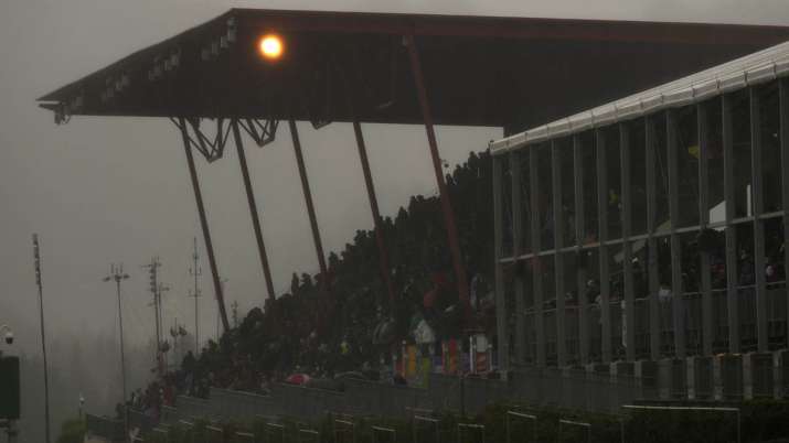 Spectators wait under an overhang during a rain delay at