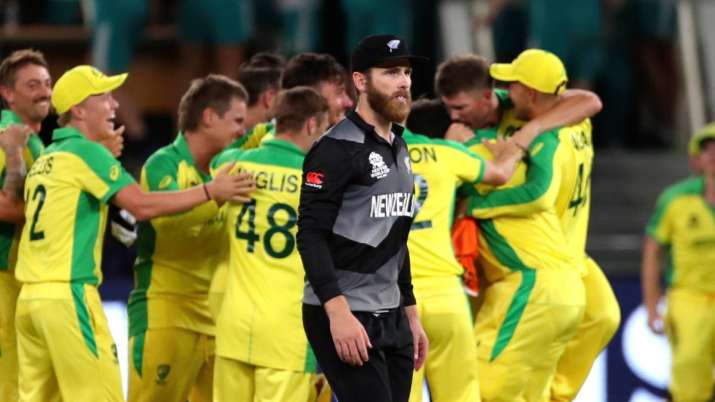New Zealand's captain Kane Williamson walks past Australian cricketers celebrating their victory in